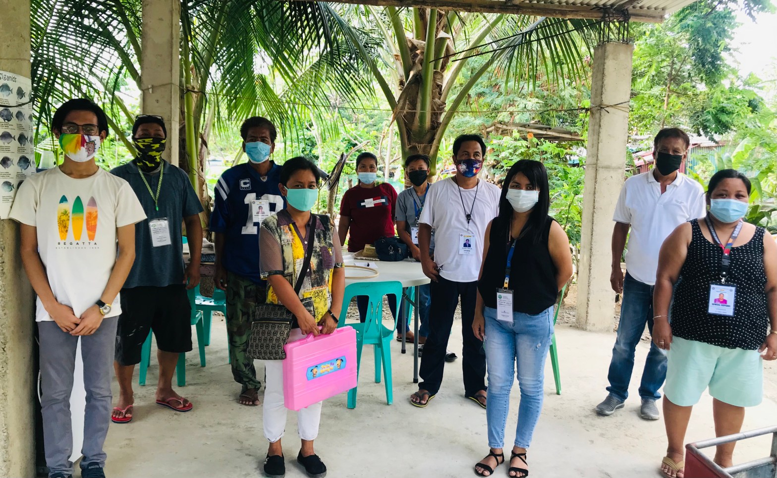An outdoor group photo of ten people, wearing masks and standing some distance apart.